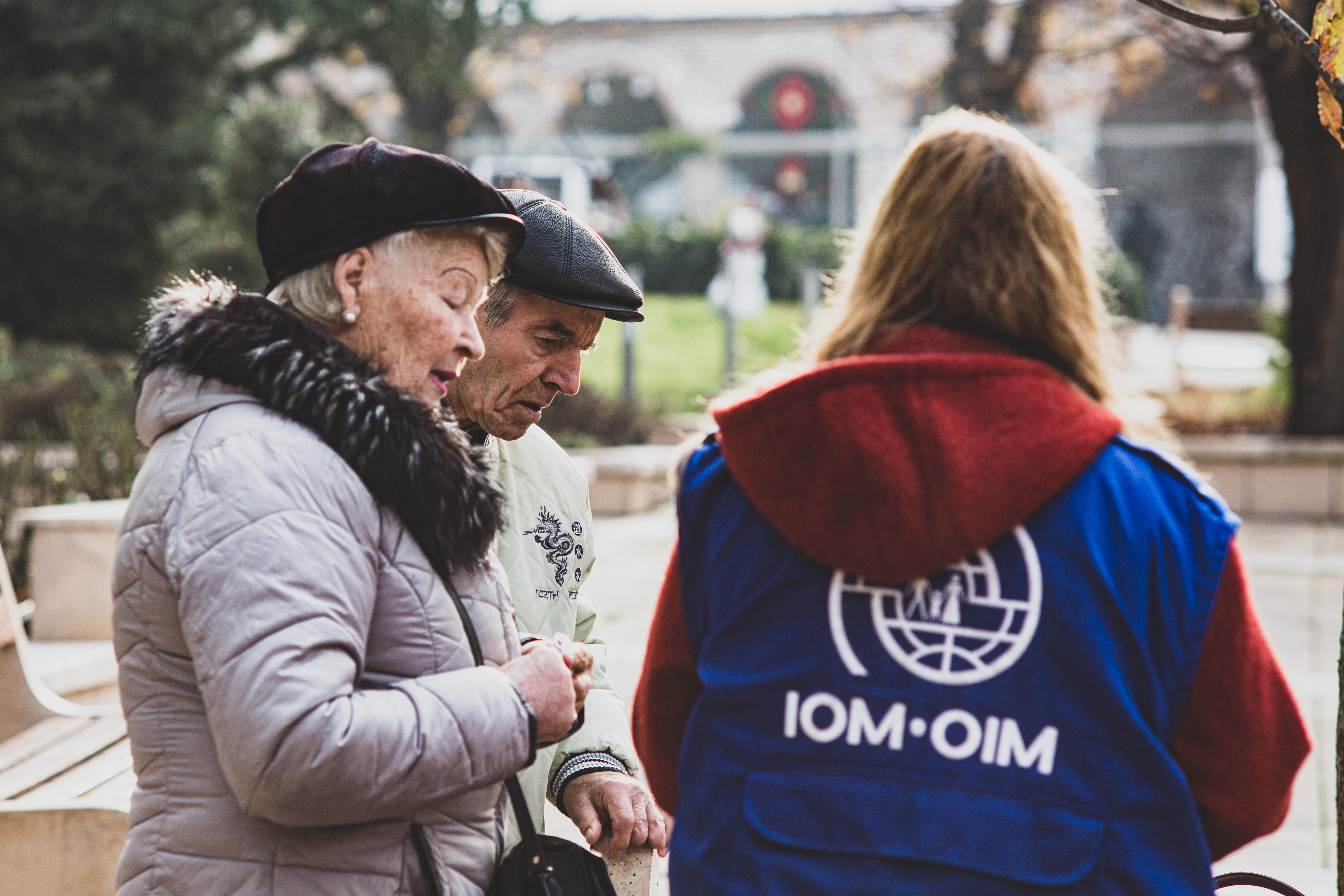 An IOM representative with an elderly couple from Ukraine 