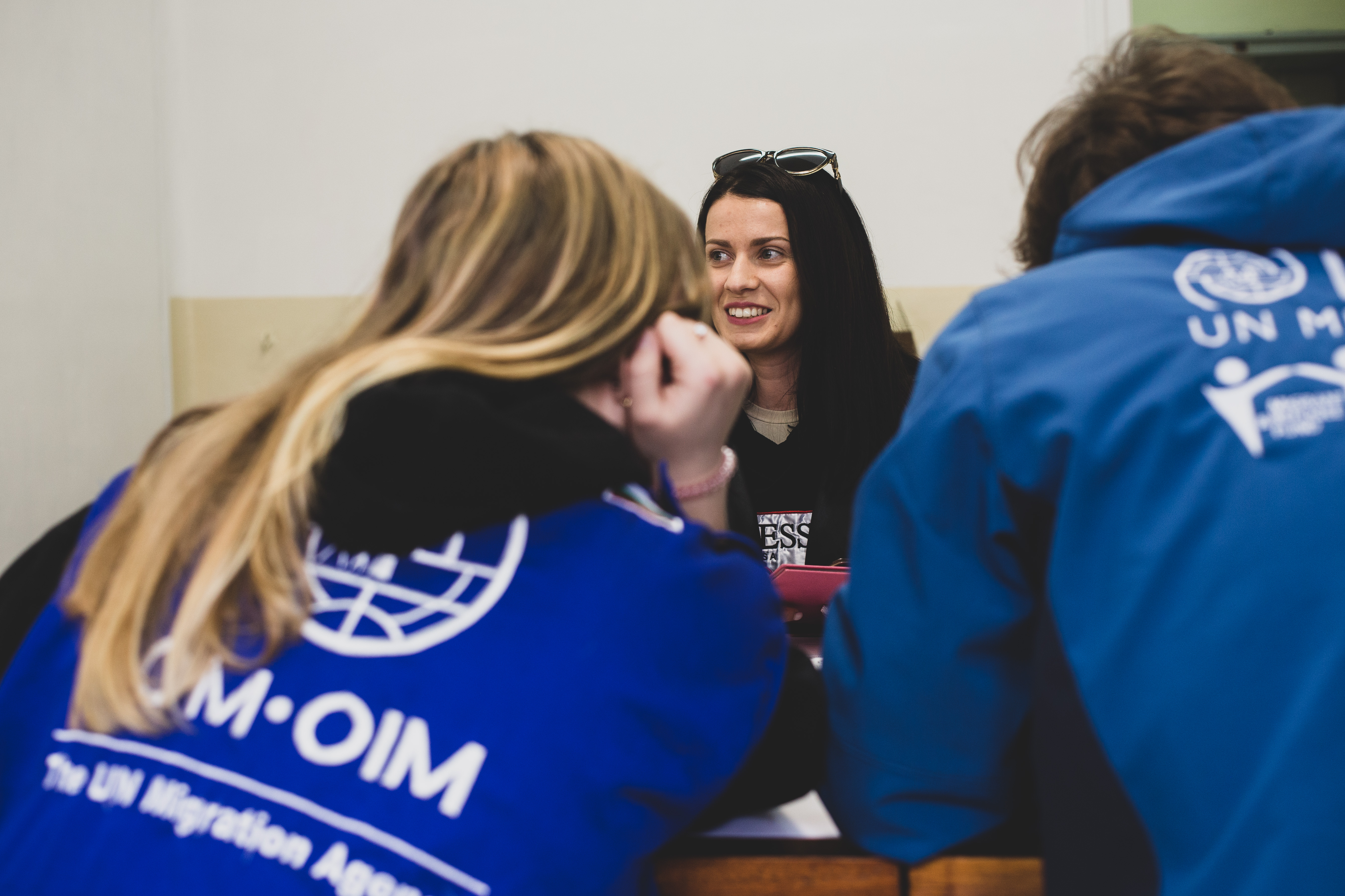 A beneficiary from Ukraine in front of IOM team members 