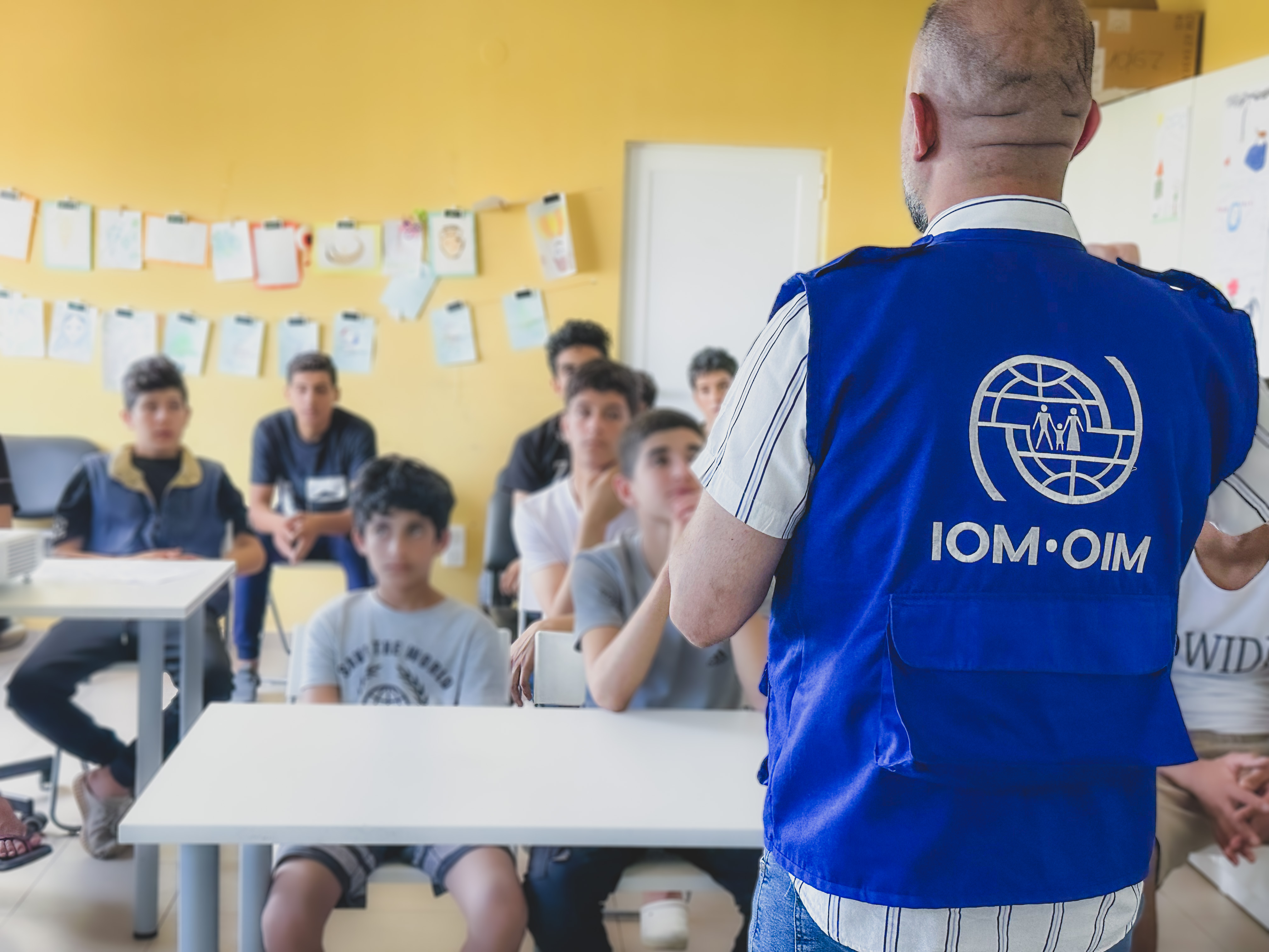 an IOM social worker in front of an audience of unaccompanied children