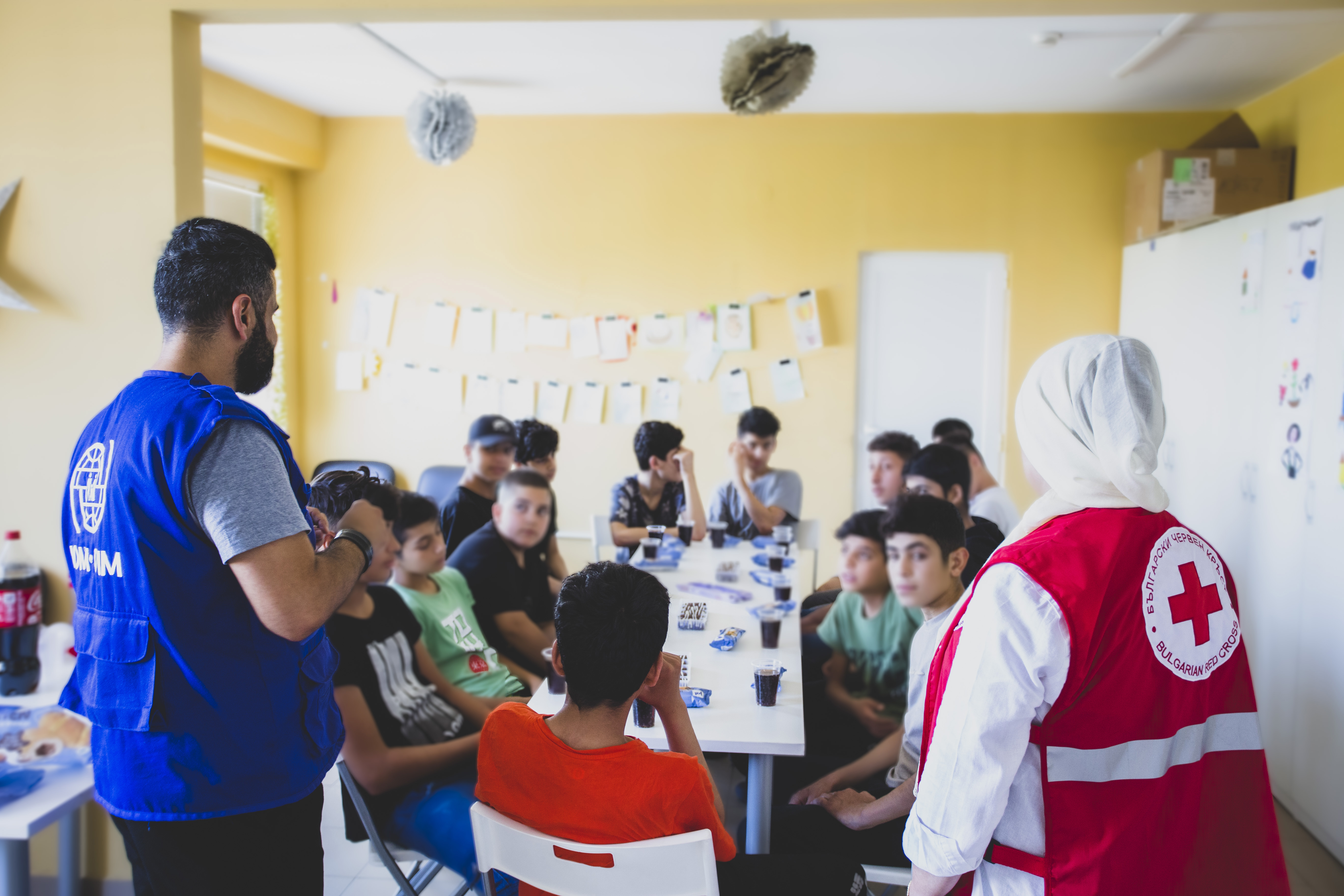 IOM social worker and a Red Cross representatives in front of unaccompanied children